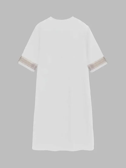White - A woman wearing a white, knee-length shift dress made of textured linen-like fabric, featuring intricate beige crochet lace trim along the deep V-neckline and elbow-length sleeve cuffs.