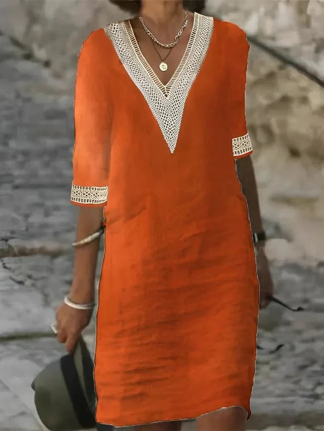 Orange - A woman wearing a white, knee-length shift dress made of textured linen-like fabric, featuring intricate beige crochet lace trim along the deep V-neckline and elbow-length sleeve cuffs.