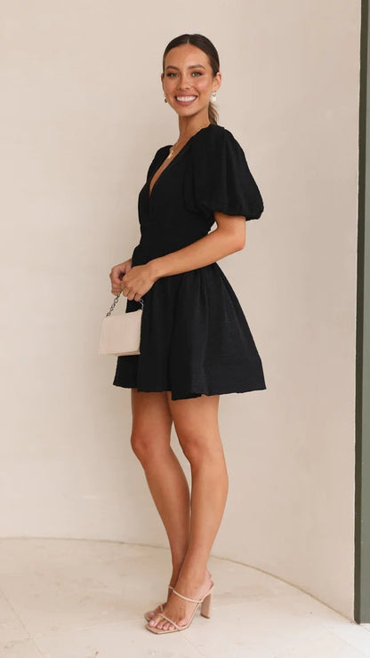 Black - A woman wearing a vibrant pink linen mini dress with a plunging V-neckline, puff sleeves, and a smocked waist, holding a beige handbag.