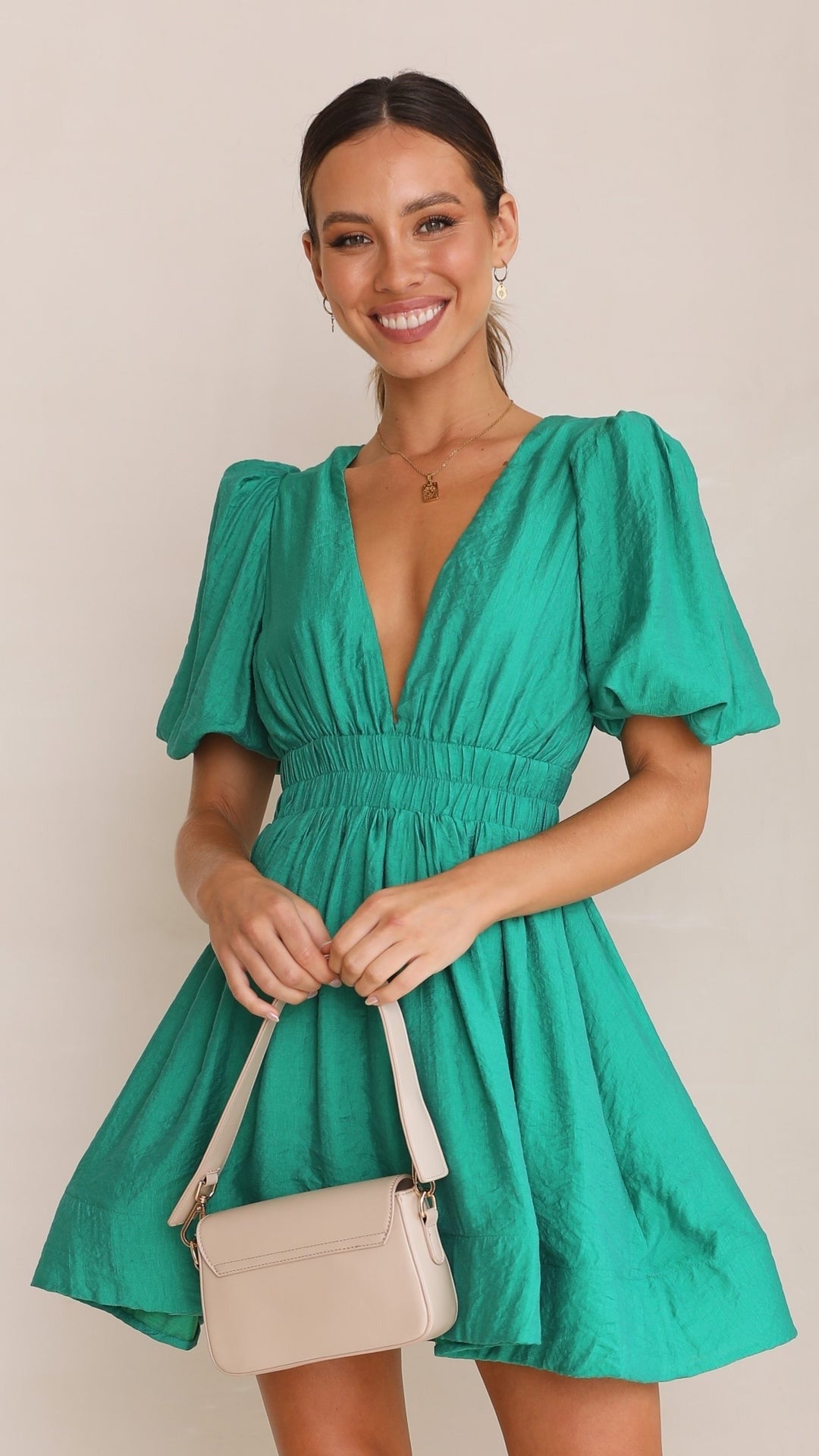 Green - A woman wearing a vibrant pink linen mini dress with a plunging V-neckline, puff sleeves, and a smocked waist, holding a beige handbag.