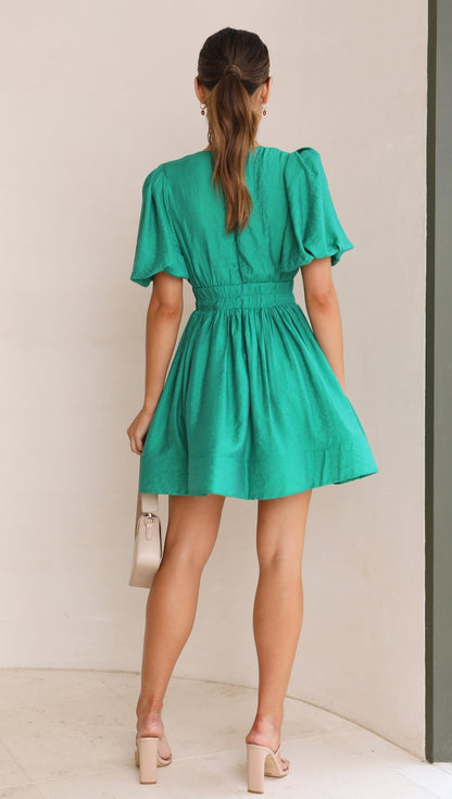 Green - A woman wearing a vibrant pink linen mini dress with a plunging V-neckline, puff sleeves, and a smocked waist, holding a beige handbag.