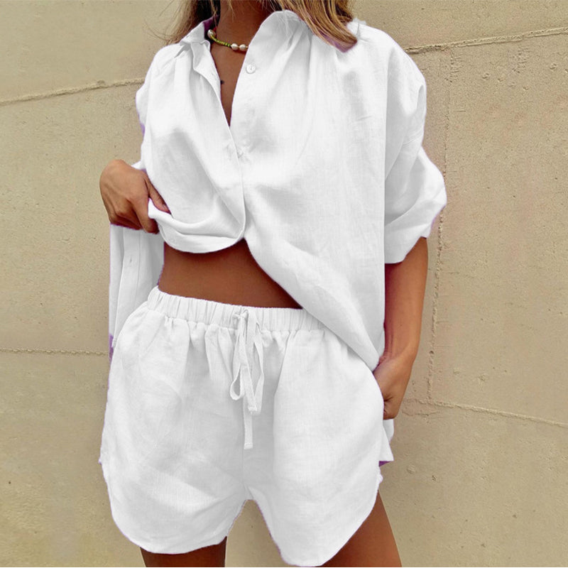 White - Woman wearing a relaxed light green linen button-down blouse and matching drawstring shorts, holding a woven straw tote bag.