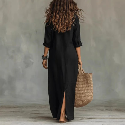 Black - A woman wearing a white textured linen maxi shirt dress with rolled sleeves, a partial button placket, and a front split, carrying a woven straw tote bag.