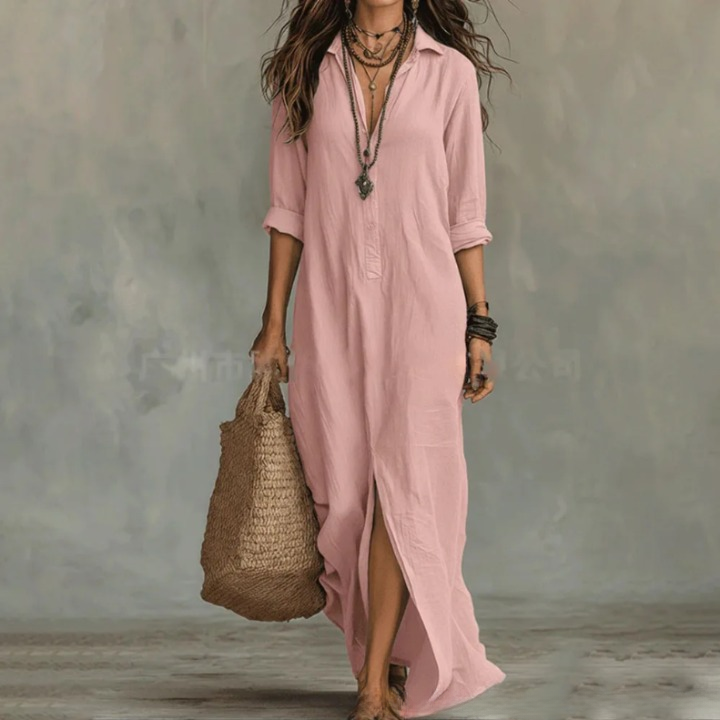 Pink - A woman wearing a white textured linen maxi shirt dress with rolled sleeves, a partial button placket, and a front split, carrying a woven straw tote bag.