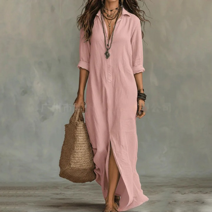 Pink - A woman wearing a white textured linen maxi shirt dress with rolled sleeves, a partial button placket, and a front split, carrying a woven straw tote bag.