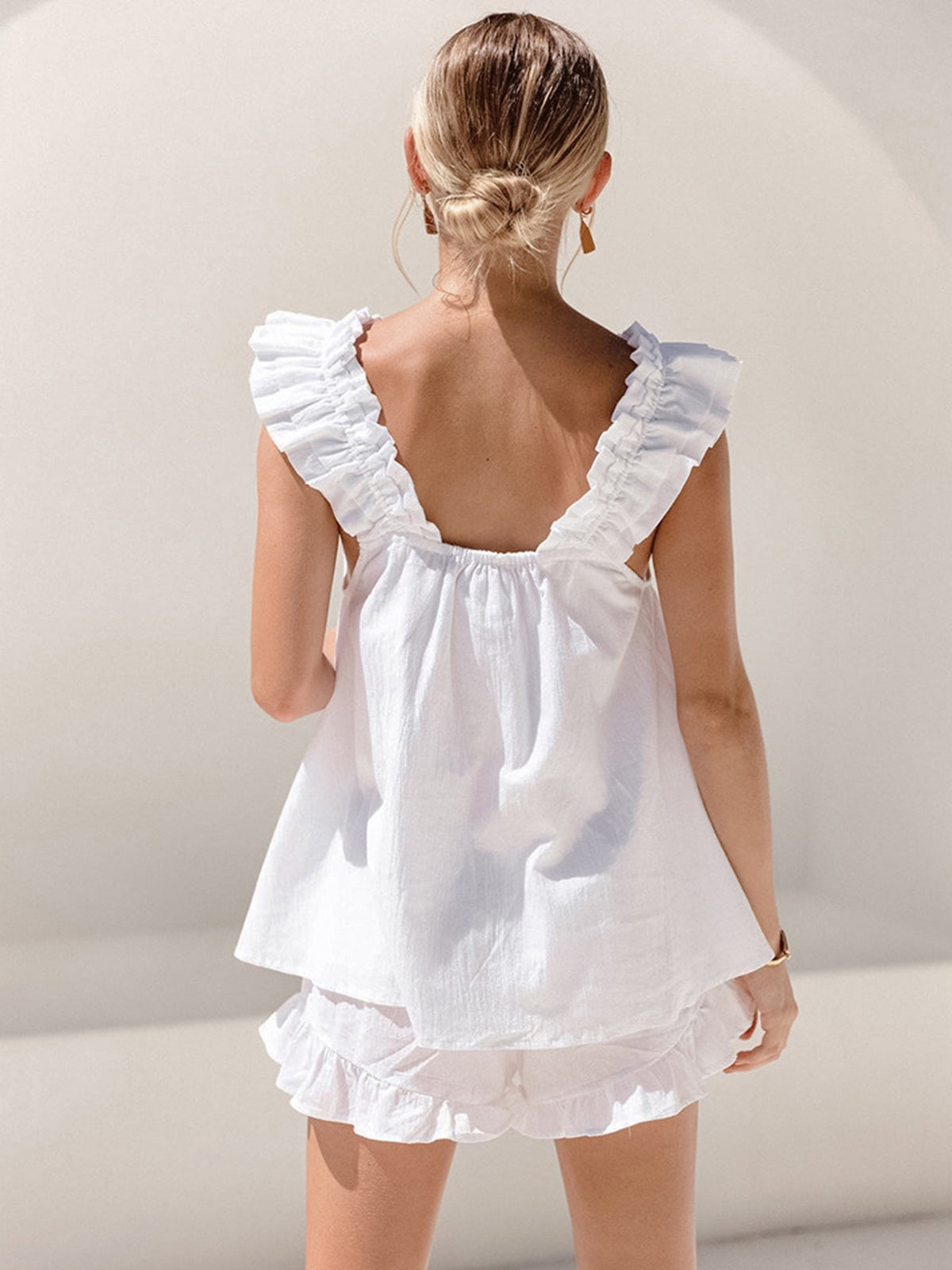 White - White linen babydoll top with ruffled flutter straps and a gathered square neckline, worn with matching ruffled shorts.