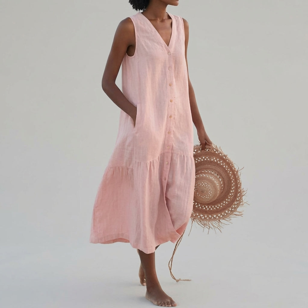 Pink - A woman wearing a sleeveless white linen midi dress with a V-neck, button-down front, and tiered skirt, holding a wide-brimmed straw hat against a neutral background.