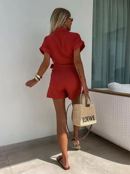 Red - Woman wearing a rust-colored linen-blend mini dress with a collar, deep V-neck, and tie waist, styled with sandals and a straw bag.