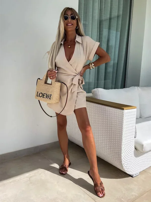 Khaki - Woman wearing a rust-colored linen-blend mini dress with a collar, deep V-neck, and tie waist, styled with sandals and a straw bag.