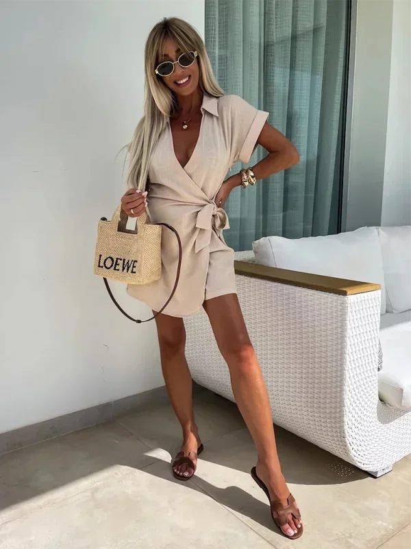 Khaki - Woman wearing a rust-colored linen-blend mini dress with a collar, deep V-neck, and tie waist, styled with sandals and a straw bag.