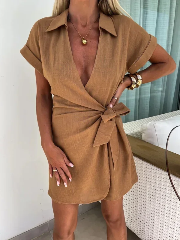 Brown - Woman wearing a rust-colored linen-blend mini dress with a collar, deep V-neck, and tie waist, styled with sandals and a straw bag.