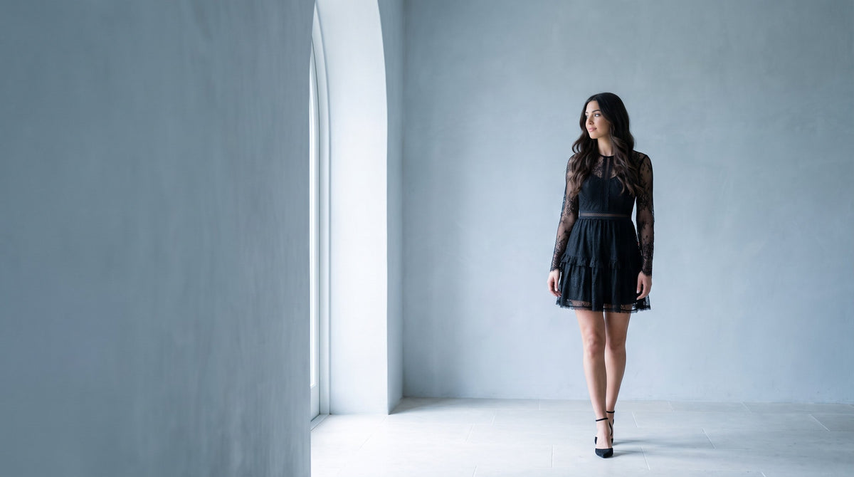 Woman in a black lace mini dress with long sheer sleeves