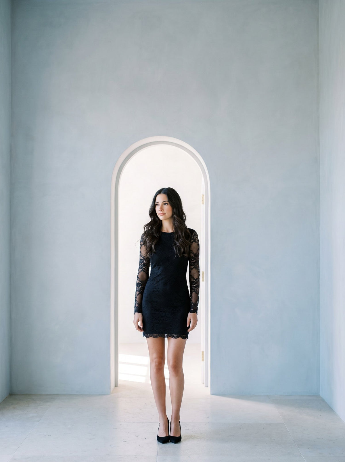 Woman in a black lace mini dress with long sheer sleeves