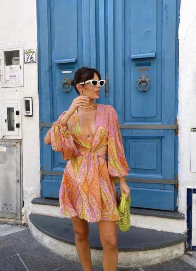 Yellow - Woman wearing a bright pink and yellow paisley print mini dress with long split sleeves, a deep V-neck, and waist cutouts.