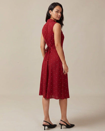 Red - A woman wearing a sleeveless dark red midi dress with white pin dots, featuring a notched collar, button-down front, and side pockets.