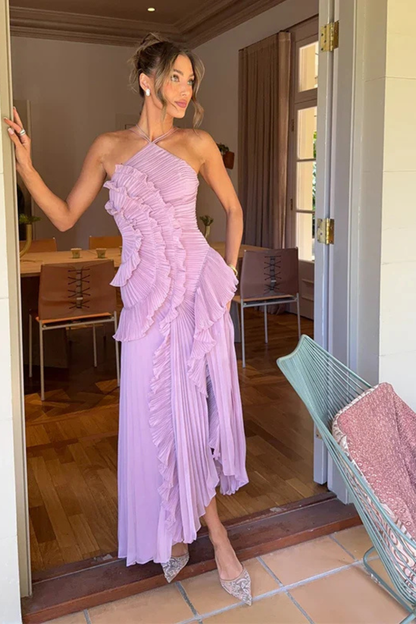 Purple - A woman wearing a sleeveless, light pink halter maxi dress made of pleated chiffon, featuring a cascading ruffle down the front and an asymmetrical high-low hemline.