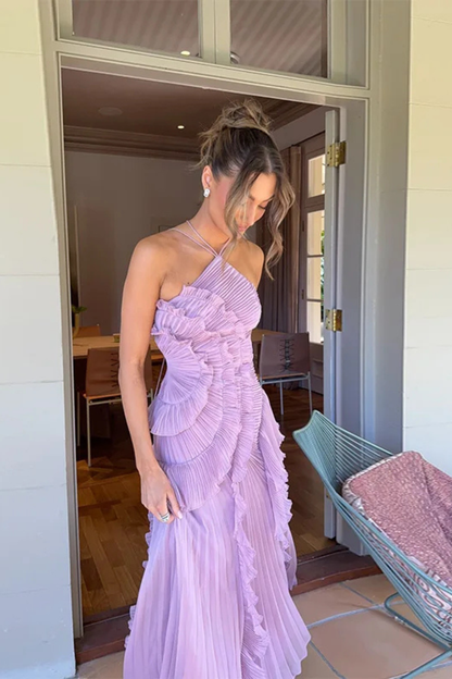 Purple - A woman wearing a sleeveless, light pink halter maxi dress made of pleated chiffon, featuring a cascading ruffle down the front and an asymmetrical high-low hemline.