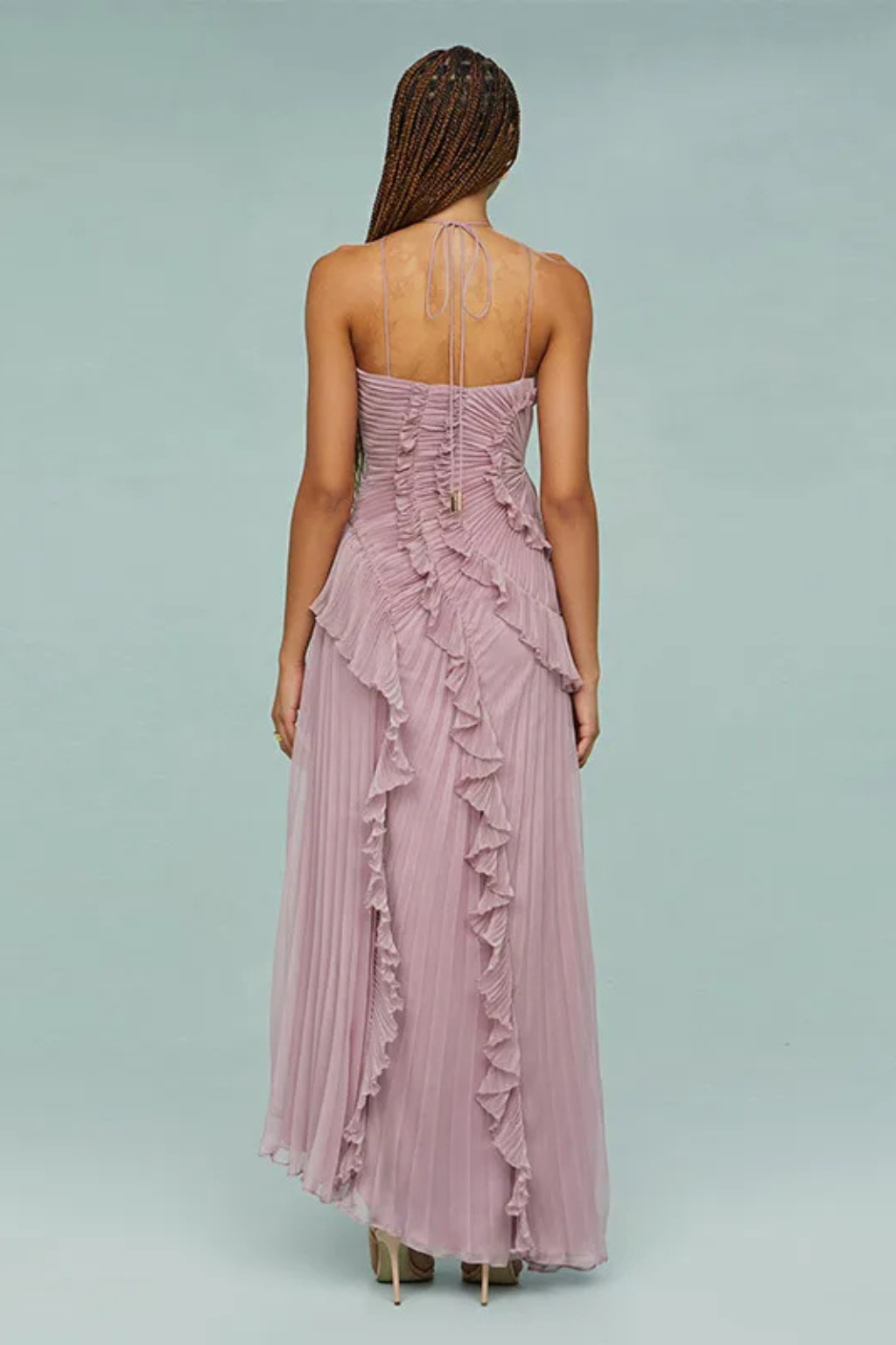 Purple - A woman wearing a sleeveless, light pink halter maxi dress made of pleated chiffon, featuring a cascading ruffle down the front and an asymmetrical high-low hemline.