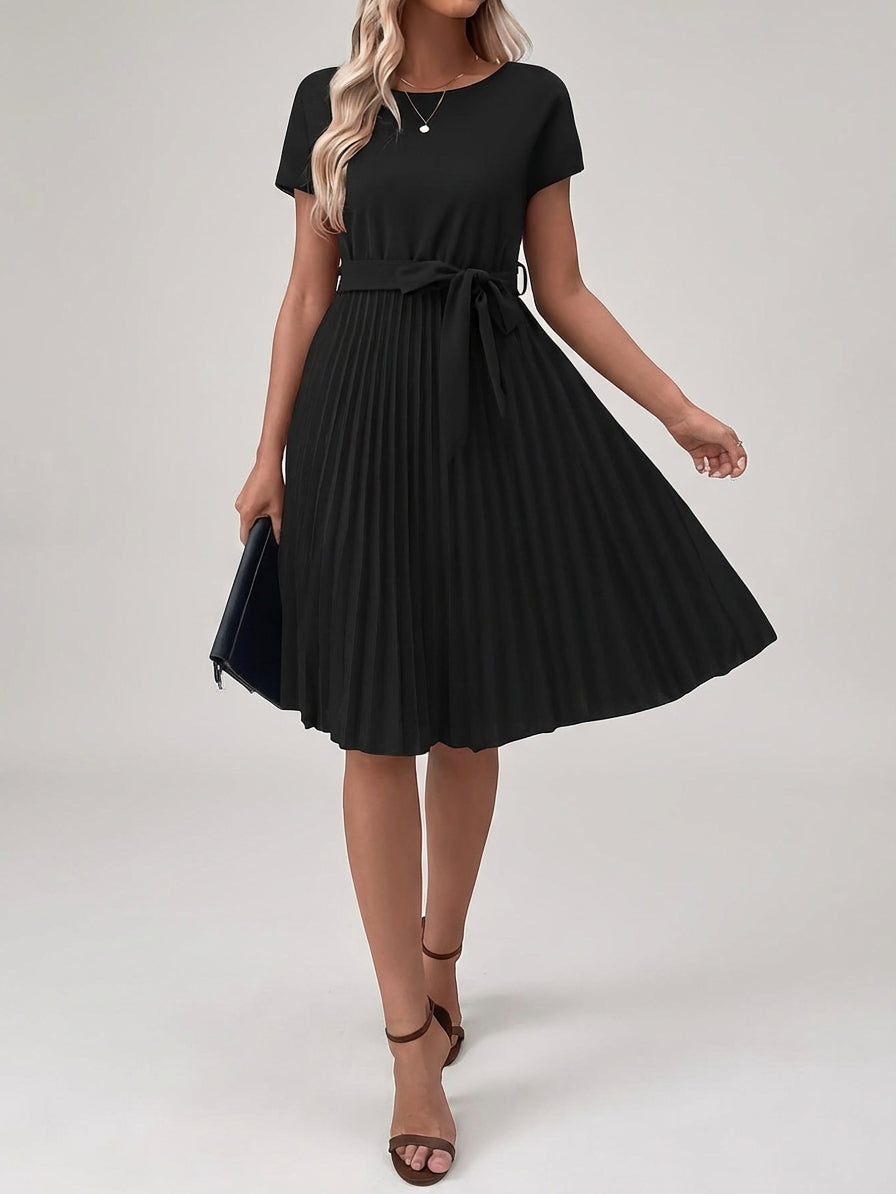 Black - A woman wearing a short-sleeve, crew-neck burgundy midi dress with a belted waist and a pleated accordion skirt, holding a black clutch.