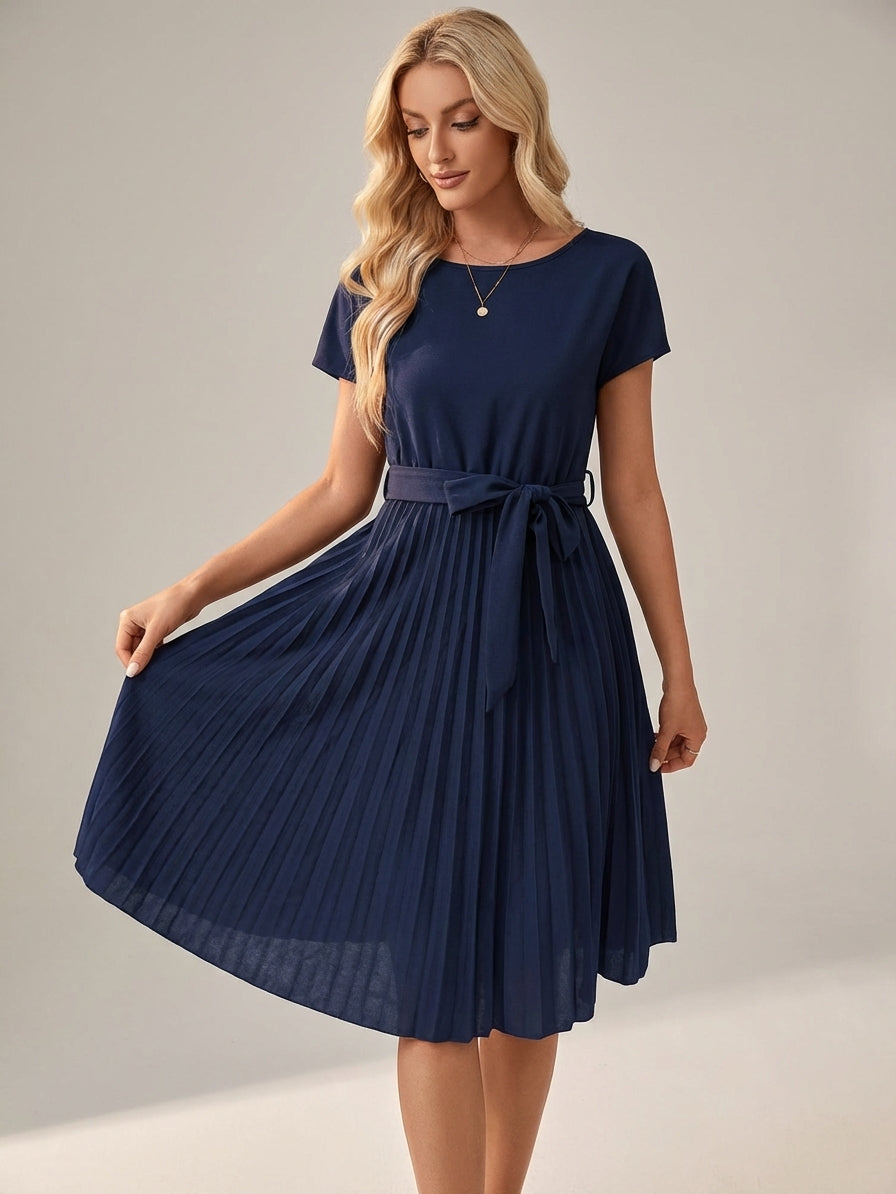 Navy - A woman wearing a short-sleeve, crew-neck burgundy midi dress with a belted waist and a pleated accordion skirt, holding a black clutch.