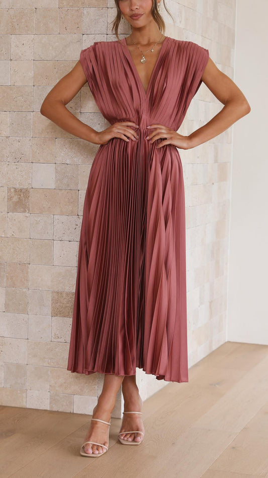 Woman wearing a dusty rose pleated midi dress with a deep V-neckline and banded waist.