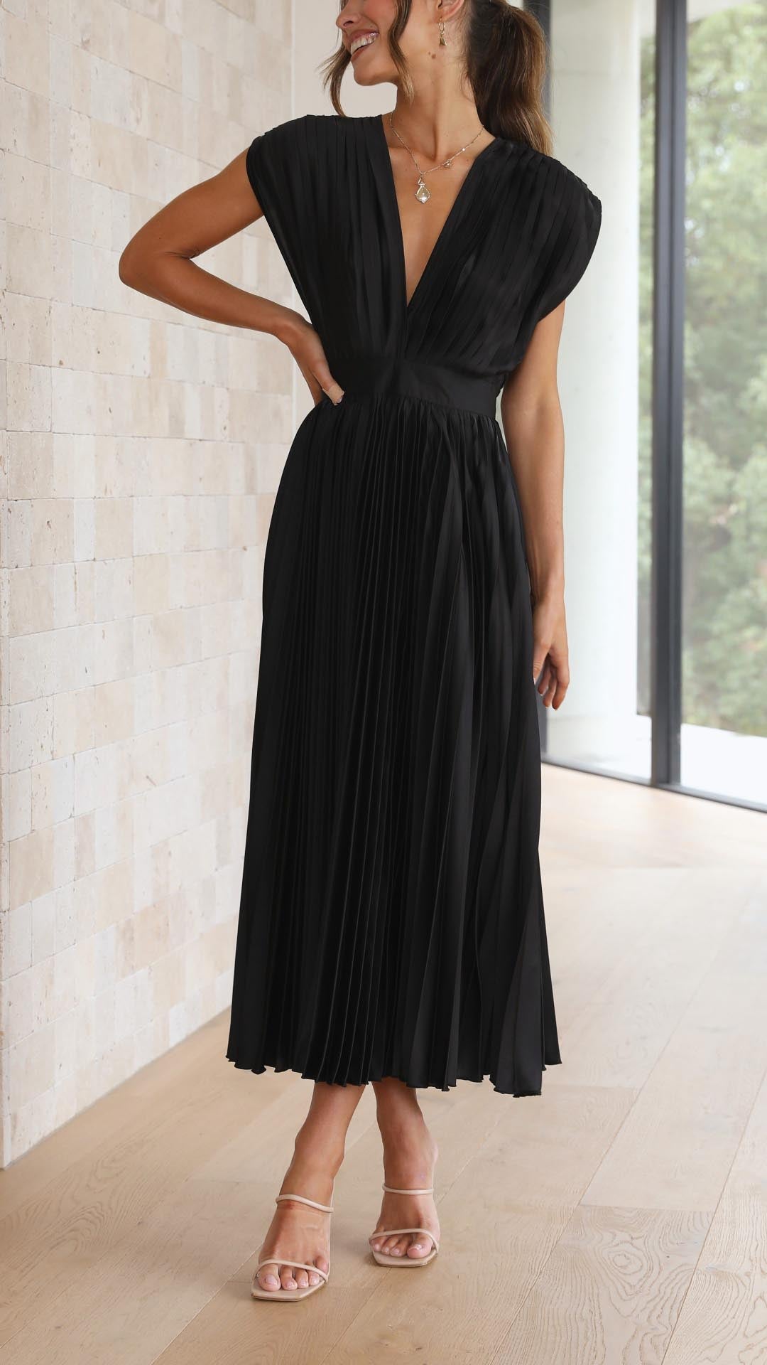 Champagne - Woman wearing a dusty rose pleated midi dress with a deep V-neckline and banded waist.