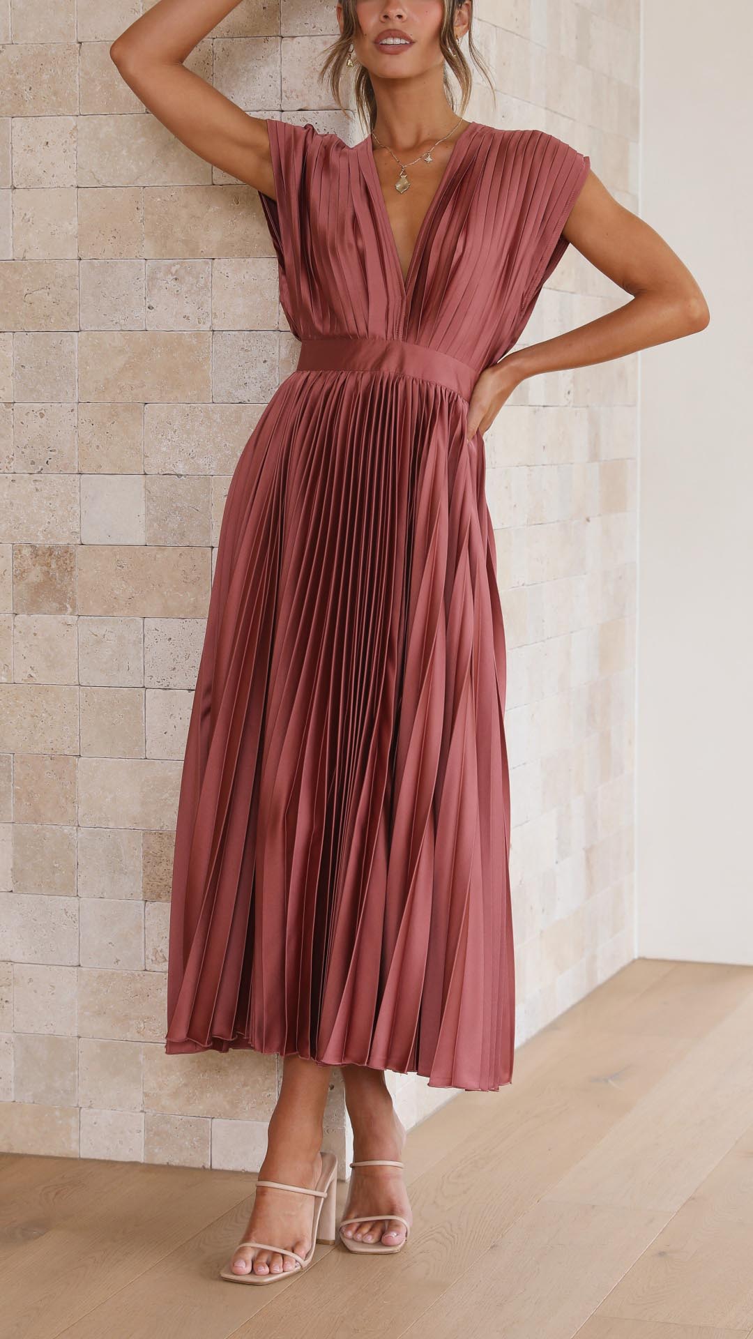 Grey - Woman wearing a dusty rose pleated midi dress with a deep V-neckline and banded waist.