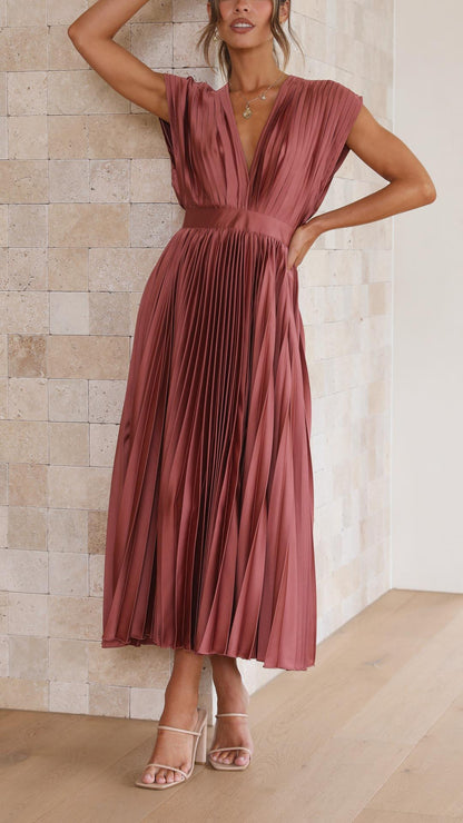 Grey - Woman wearing a dusty rose pleated midi dress with a deep V-neckline and banded waist.