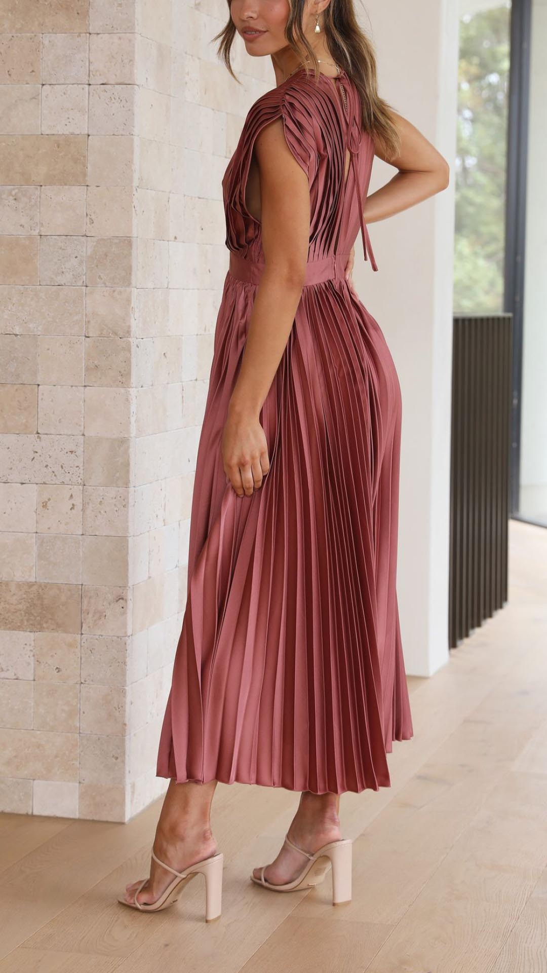 Antique Pink - Woman wearing a dusty rose pleated midi dress with a deep V-neckline and banded waist.