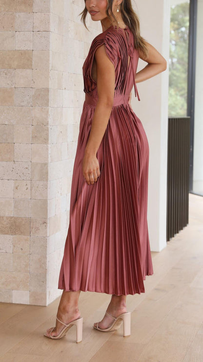 Antique Pink - Woman wearing a dusty rose pleated midi dress with a deep V-neckline and banded waist.
