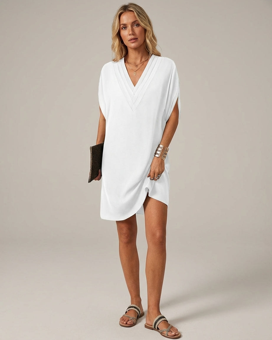 White - A woman wearing an olive green crepe shift dress with a pleated V-neckline, split short sleeves, and a relaxed silhouette.