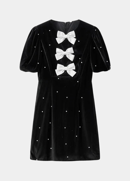 Black with pearls - Black mini dress with white polka dots, featuring short puff sleeves, a center front cutout, and three contrasting white 3D bows down the bodice.