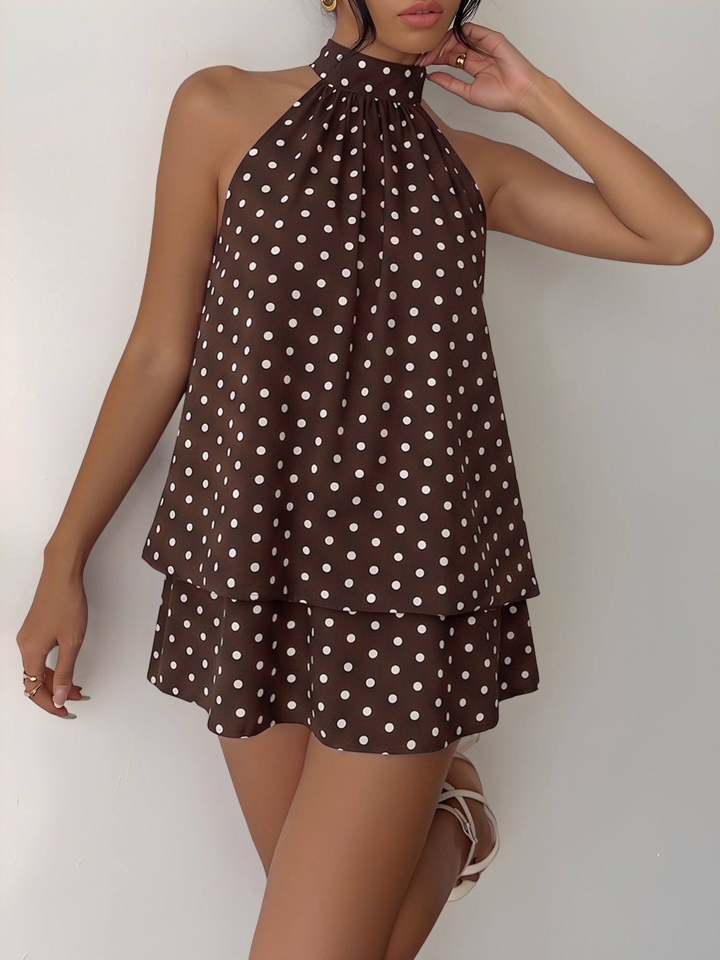 Coffee - Woman wearing a sleeveless polka dot halter mini dress with a tiered drape against a plain background