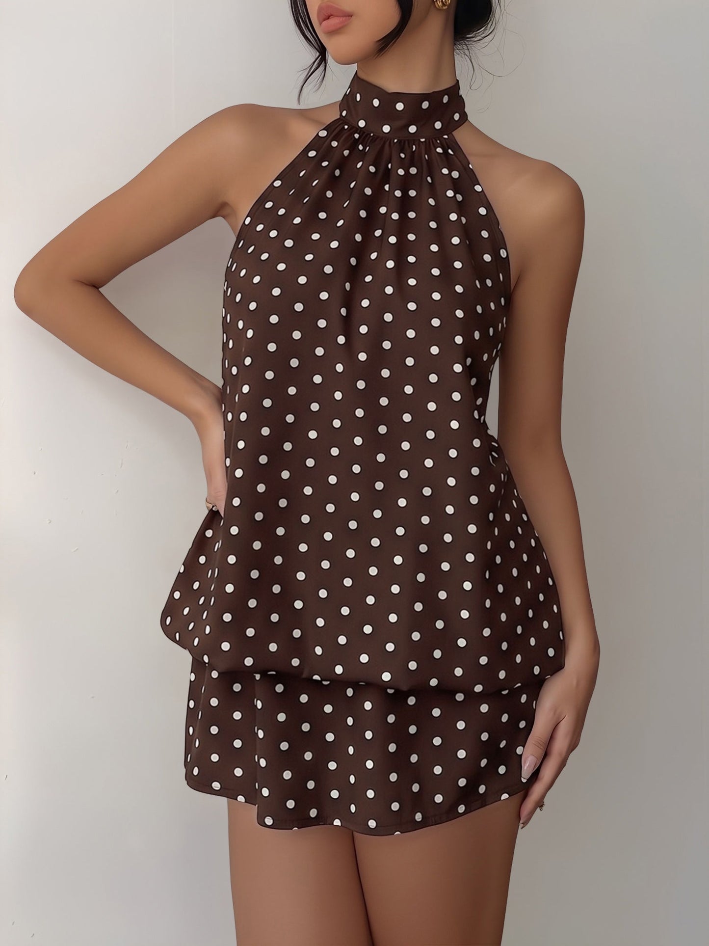 Coffee - Woman wearing a sleeveless polka dot halter mini dress with a tiered drape against a plain background