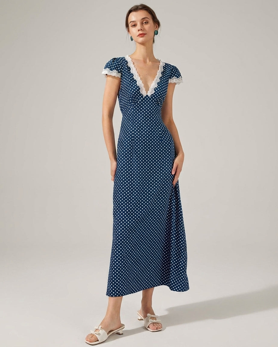 Navy - A woman wearing a navy blue and white polka dot midi dress with white lace trim along the V-neckline and cap sleeves, paired with white low-heeled slide sandals.