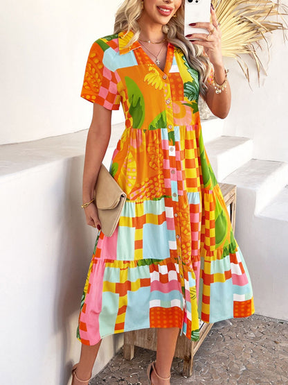 Tangerine - A woman wearing a short-sleeve, collared maxi dress with a colorful retro floral print, featuring a button-down front and a tiered skirt.