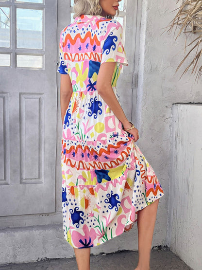 Multicolor - A woman wearing a short-sleeve, collared maxi dress with a colorful retro floral print, featuring a button-down front and a tiered skirt.