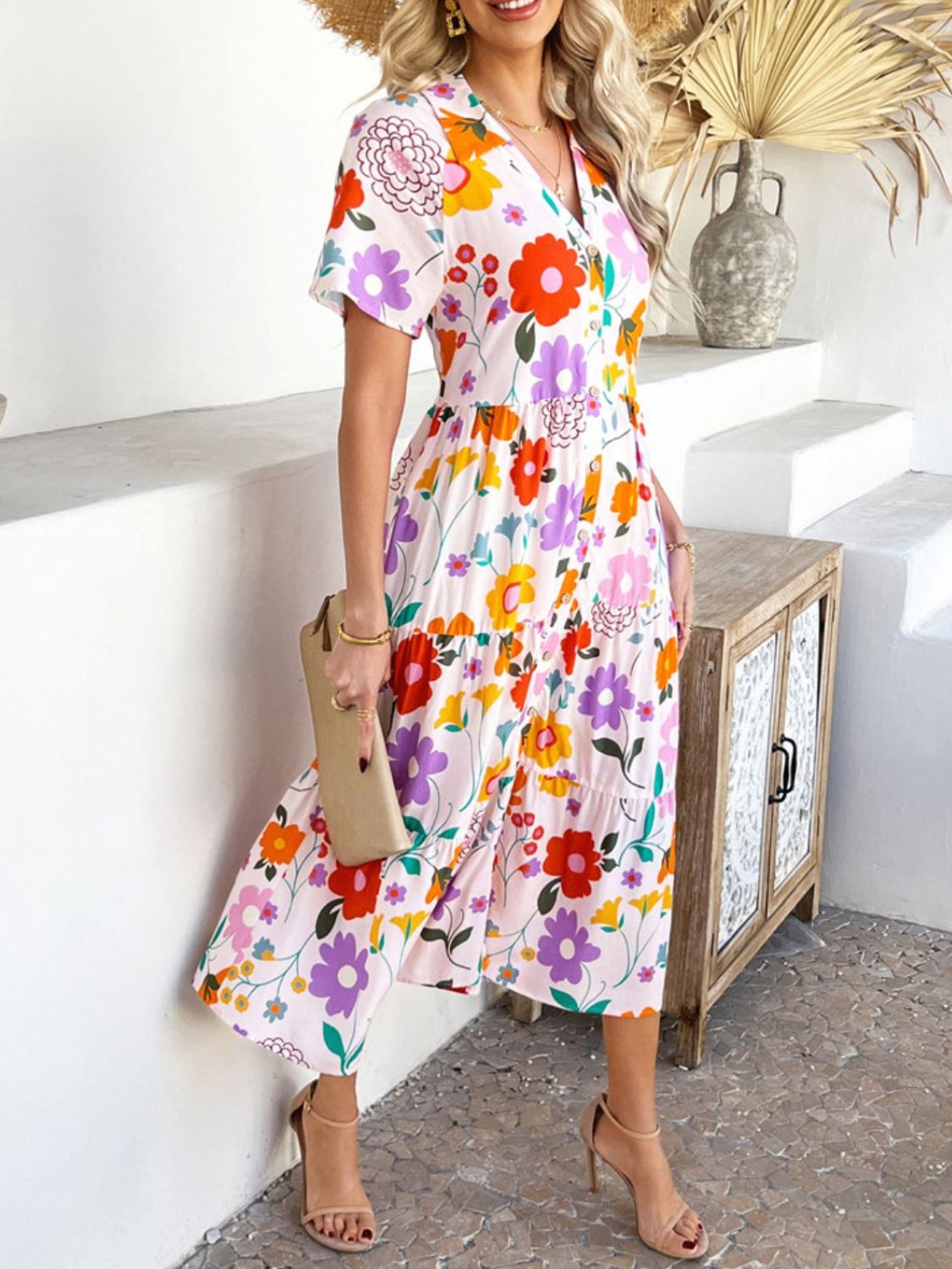 Blush Pink - A woman wearing a short-sleeve, collared maxi dress with a colorful retro floral print, featuring a button-down front and a tiered skirt.