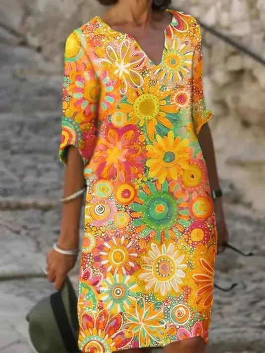 Yellow - A woman wearing a vibrant retro floral print shift dress with a V-neckline and short sleeves, featuring a colorful yellow, orange, and green pattern.