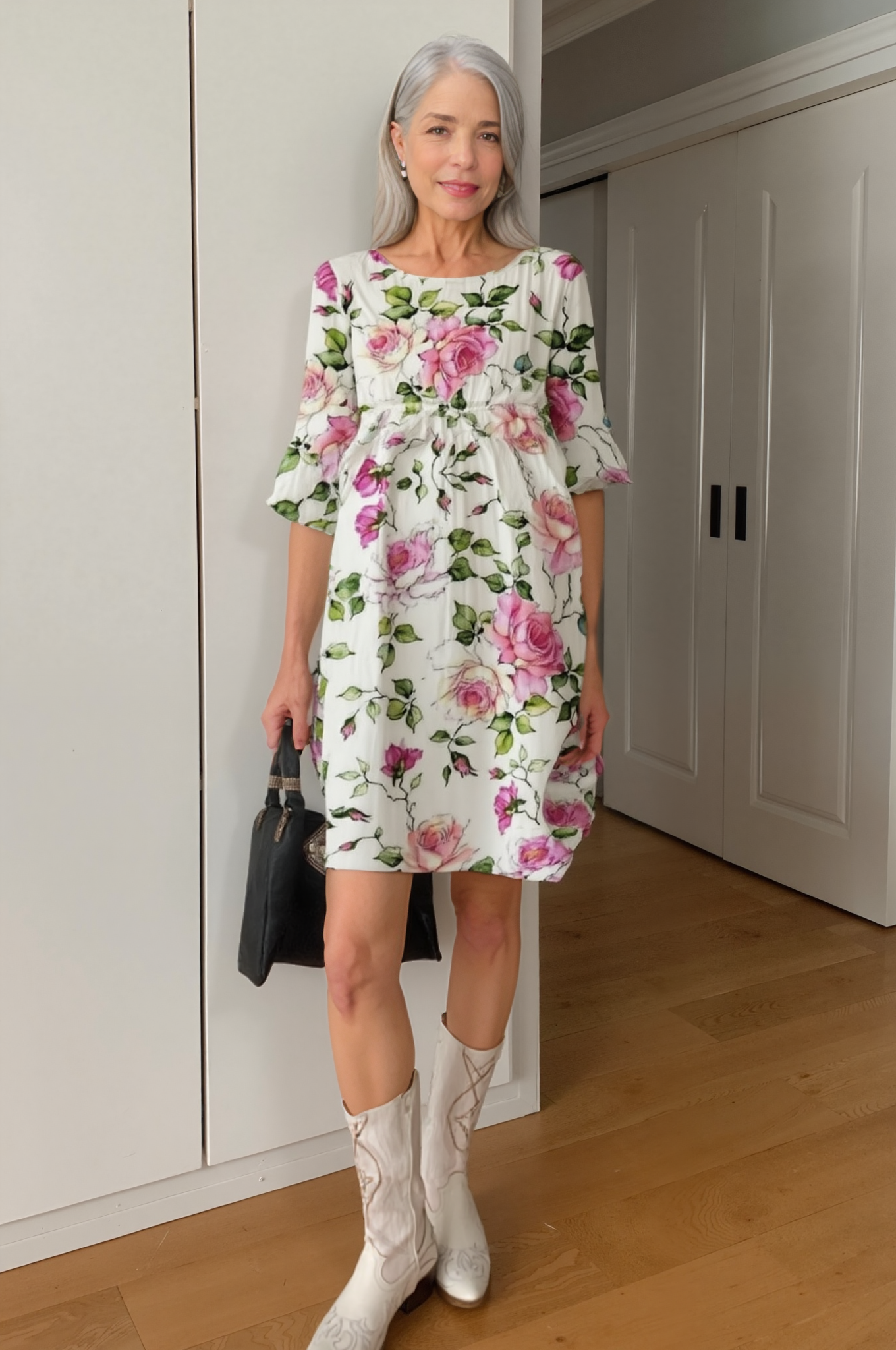 Floral - A woman on a beach wearing a white midi dress featuring a pink rose and green leaf print, three-quarter sleeves, and a relaxed linen-texture drape.