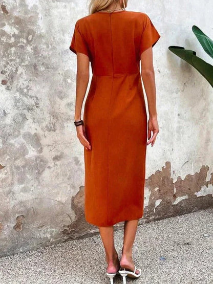 Orange - Woman wearing a burnt orange midi dress with a wrap v-neckline, side ruching, and an asymmetrical front slit.