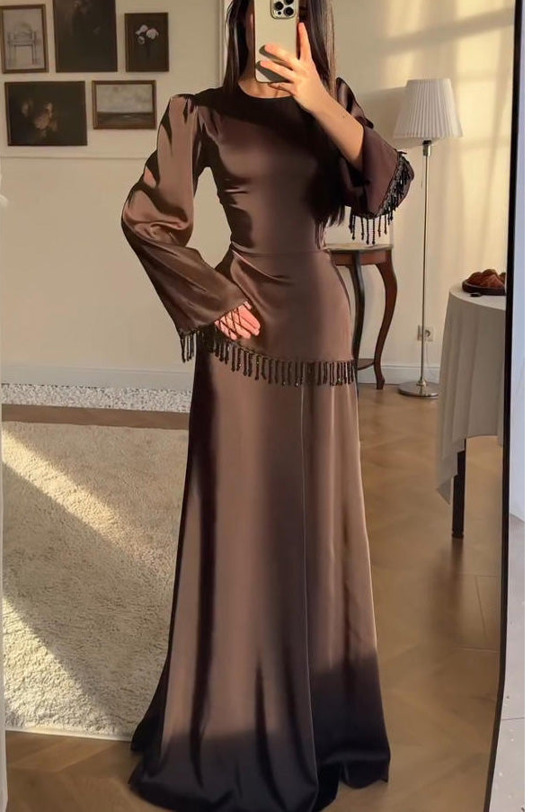 Brown - Woman wearing a chocolate brown satin long sleeve maxi dress with beaded fringe detailing at the cuffs and waistline.