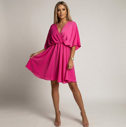 Pink - A woman wearing a light olive green satin mini dress featuring a deep V-neck, twist-front waist detail, short flutter sleeves, and a tiered asymmetric skirt, paired with nude heeled sandals.