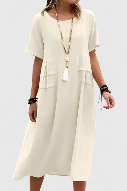 Beige - Woman wearing a light-colored, short-sleeve midi dress with front patch pockets and a relaxed A-line silhouette.