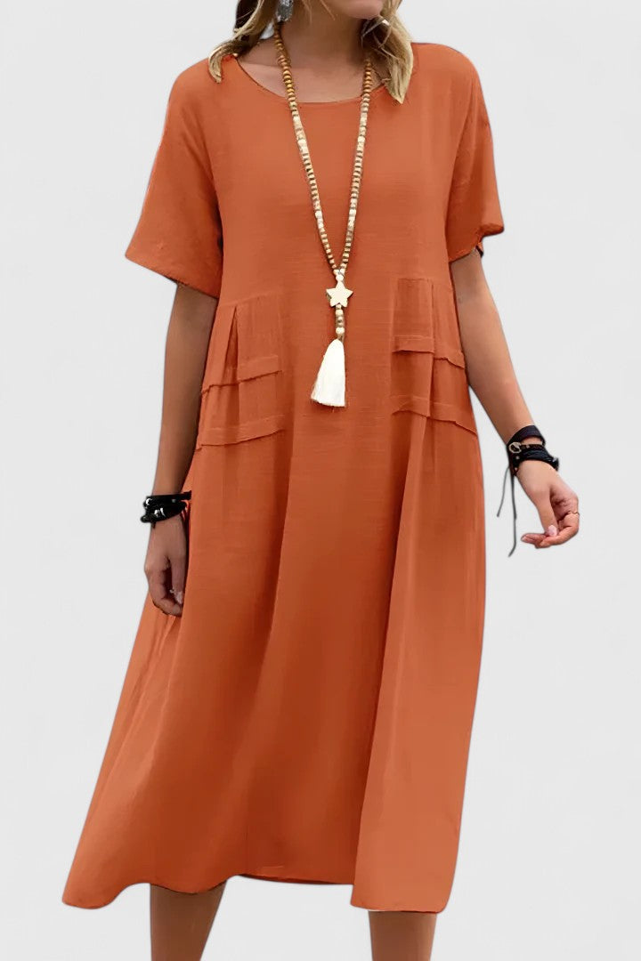 Orange - Woman wearing a light-colored, short-sleeve midi dress with front patch pockets and a relaxed A-line silhouette.