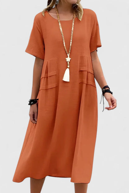 Orange - Woman wearing a light-colored, short-sleeve midi dress with front patch pockets and a relaxed A-line silhouette.