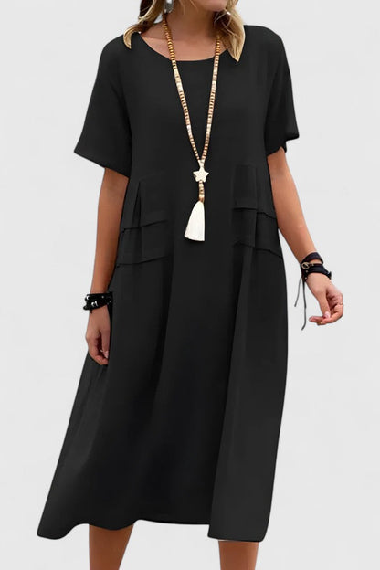 Black - Woman wearing a light-colored, short-sleeve midi dress with front patch pockets and a relaxed A-line silhouette.