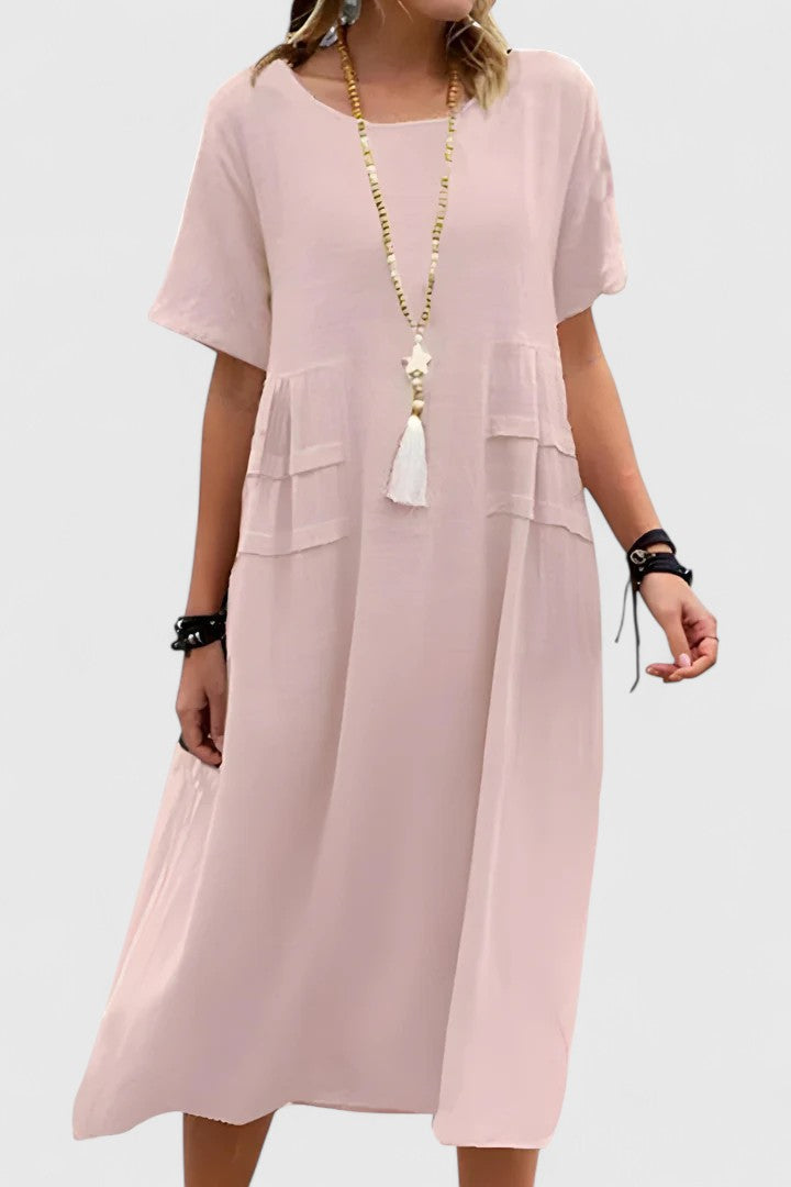Pink - Woman wearing a light-colored, short-sleeve midi dress with front patch pockets and a relaxed A-line silhouette.