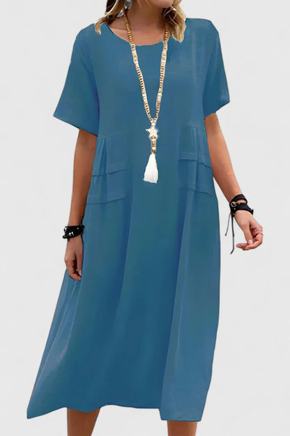 Blue - Woman wearing a light-colored, short-sleeve midi dress with front patch pockets and a relaxed A-line silhouette.
