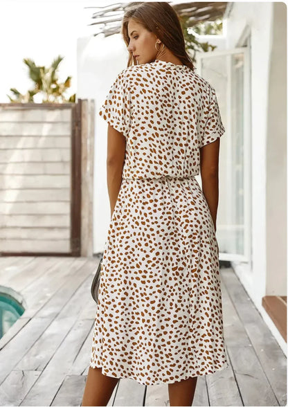 Light brown - Woman wearing a white midi shirt dress with a brown abstract spotted print, featuring a collared button-front bodice and a drawstring waist.